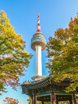 Namsan Seoul Tower above autumn trees and Korean pavilion.
