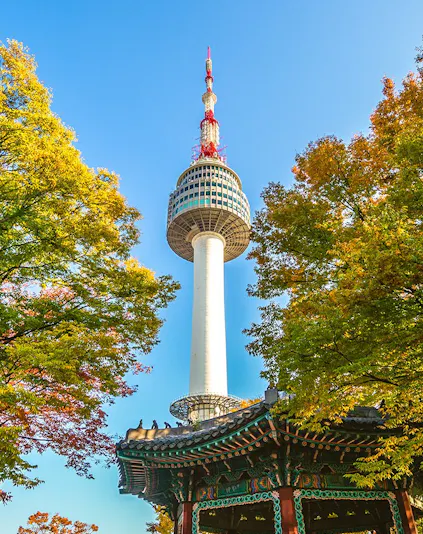 Namsan Seoul Tower above autumn trees and Korean pavilion.