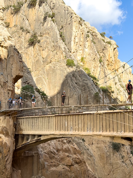 Hikers crossing suspension bridge on Caminito del Rey guided tour in Spain.