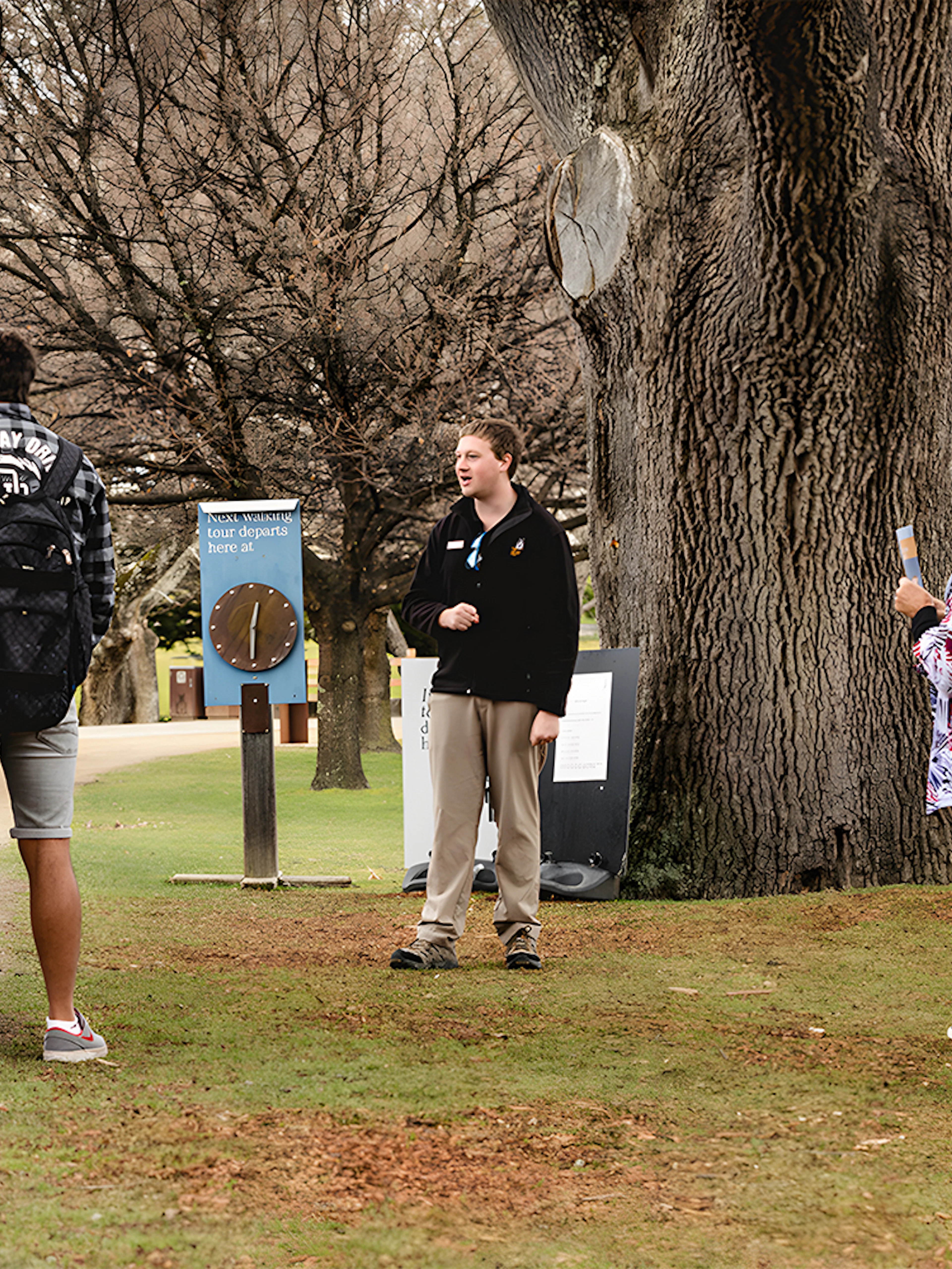 Group listening to a guide during Port Arthur tour with trees in the background.