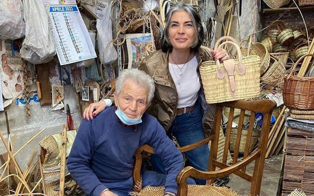 Craftsman and visitor in Ortigia workshop with handmade wicker baskets.