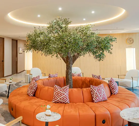 Coral Airport Lounge seating area with central tree at Suvarnabhumi Airport.