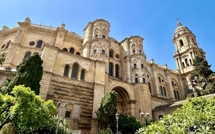 Málaga Cathedral with Renaissance architecture and lush greenery.
