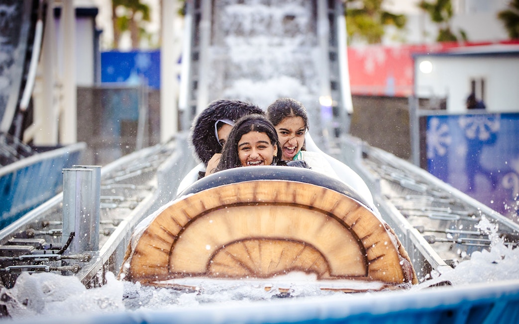 Log flume ride with smiling visitors at Lusail Winter Wonderland.