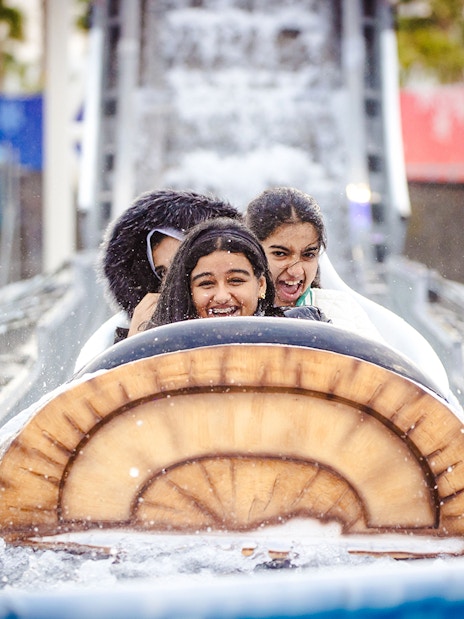 Log flume ride with smiling visitors at Lusail Winter Wonderland.