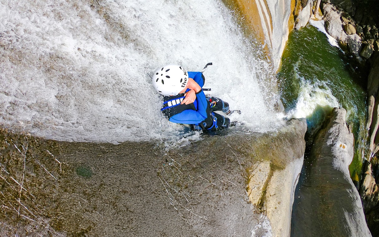 Person descending a waterfall during canyoning in Interlaken.