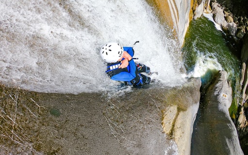 Person descending a waterfall during canyoning in Interlaken.