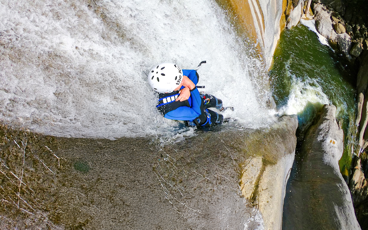 Person descending a waterfall during canyoning in Interlaken.