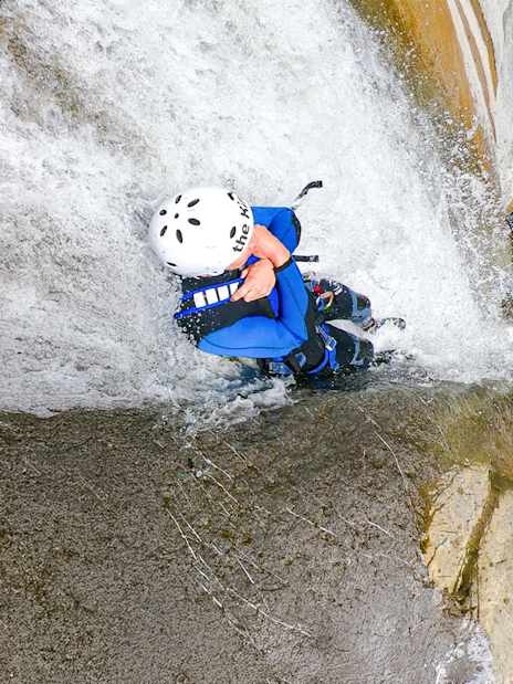 Person descending a waterfall during canyoning in Interlaken.