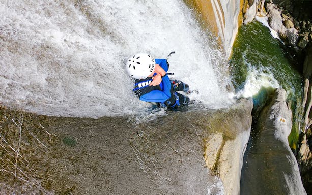 Person descending a waterfall during canyoning in Interlaken.