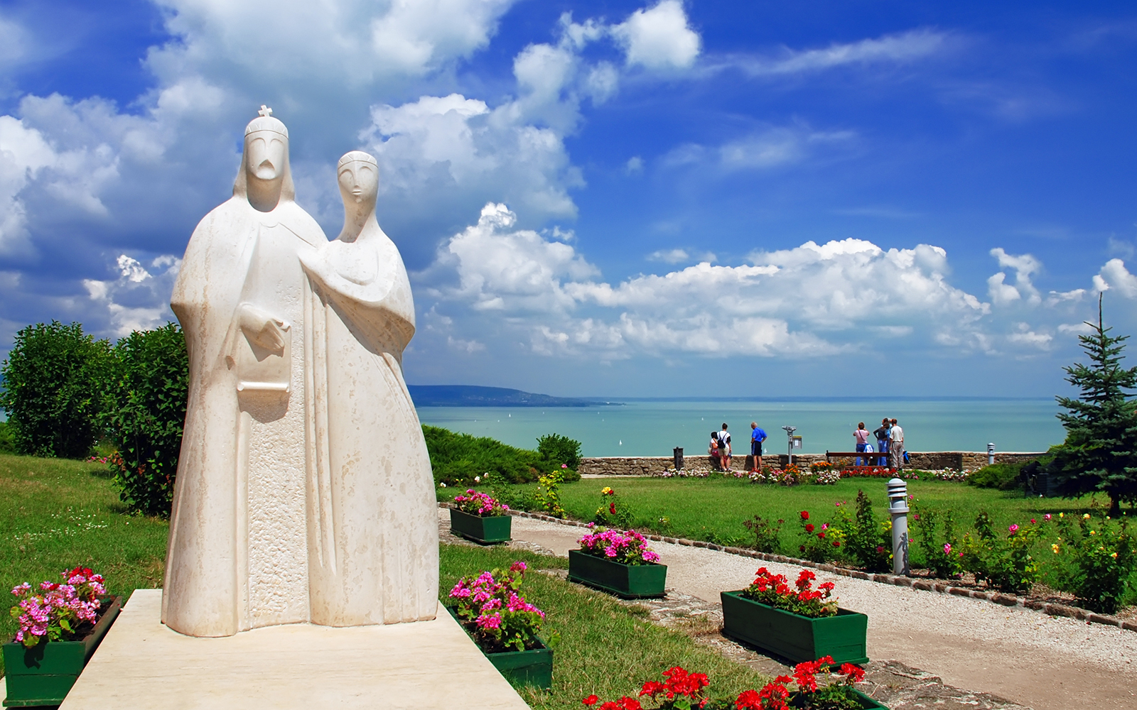 Statue in Tihany overlooking Lake Balaton with tourists enjoying the view.