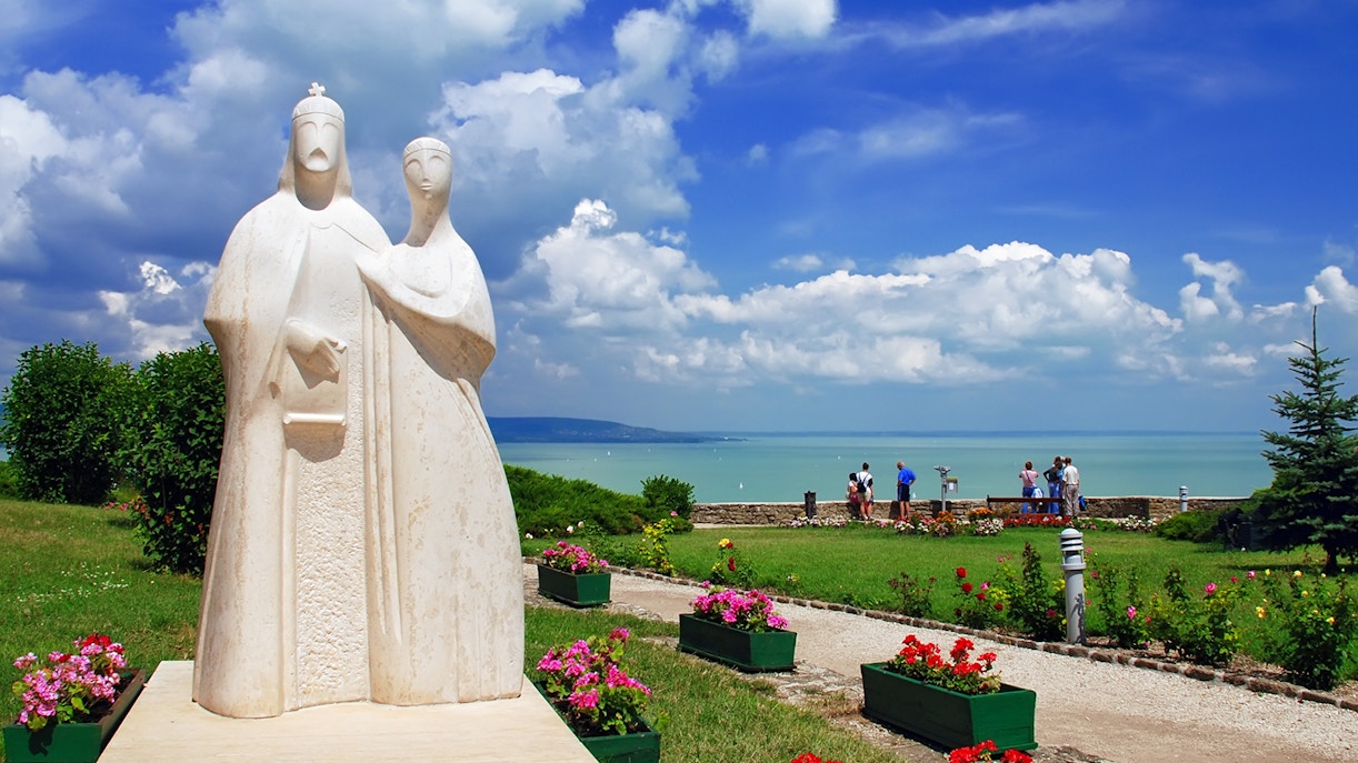 Statue in Tihany overlooking Lake Balaton with tourists enjoying the view.