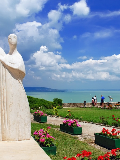 Statue in Tihany overlooking Lake Balaton with tourists enjoying the view.