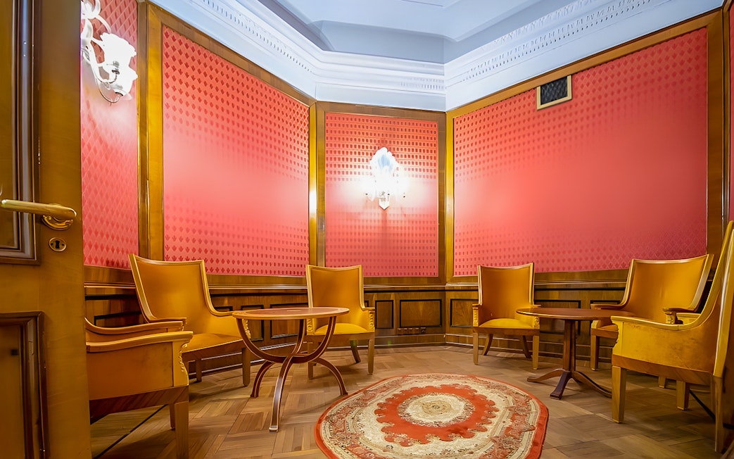 Meeting room with wooden chairs and table, red walls, and ornate rug at Palace of Culture and Science.