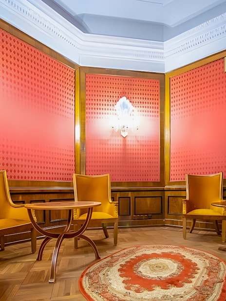 Meeting room with wooden chairs and table, red walls, and ornate rug at Palace of Culture and Science.