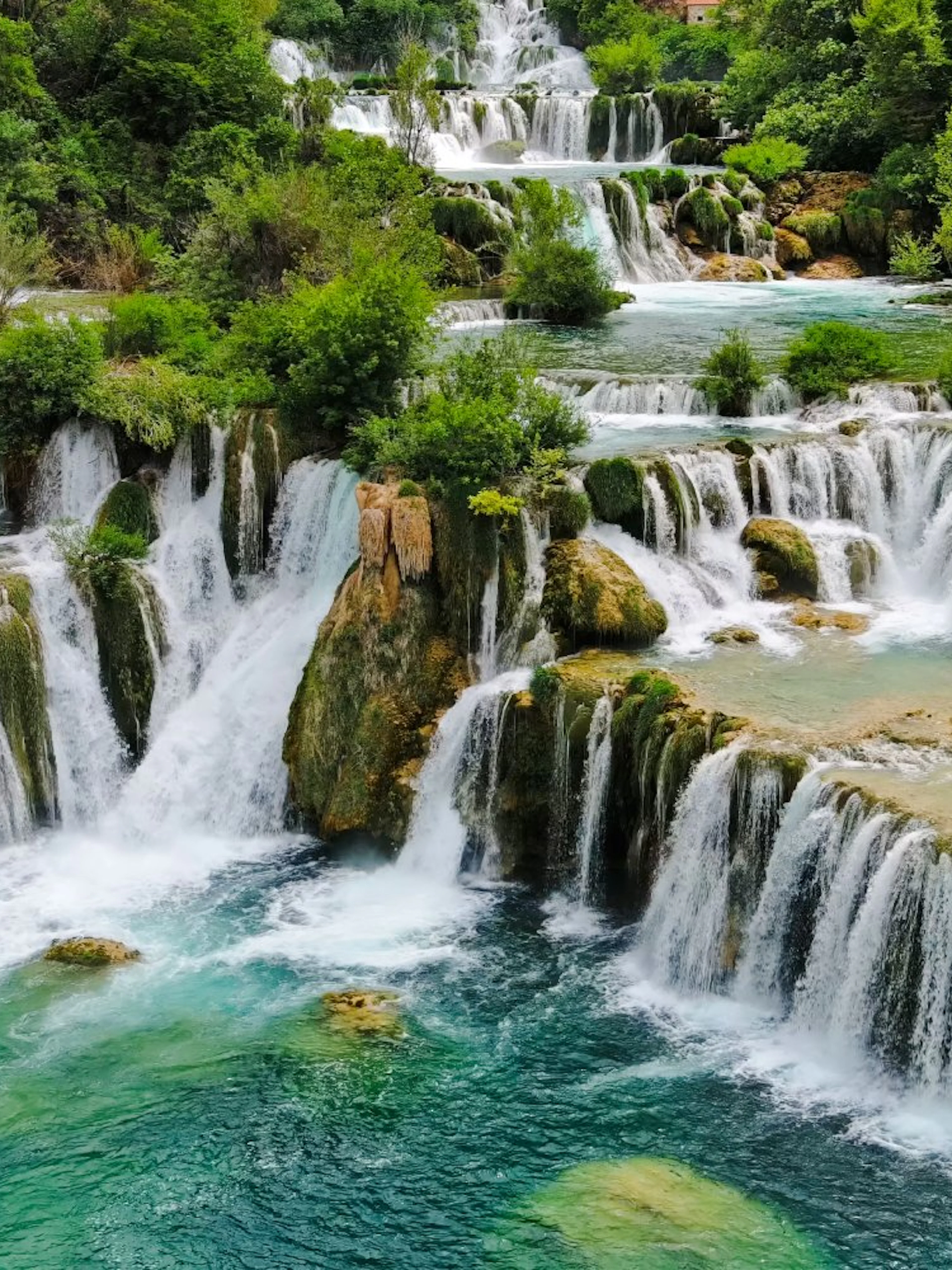 Waterfalls cascading over rocks surrounded by lush greenery at Krka National Park.