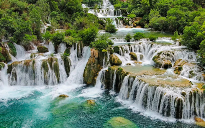 Waterfalls cascading over rocks surrounded by lush greenery at Krka National Park.