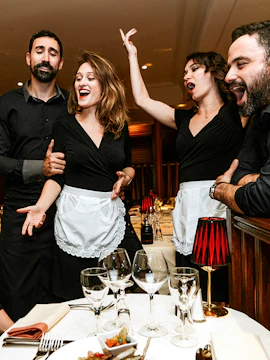 Singers performing at a dining table during the Bel Canto Experience.
