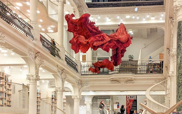 Bucharest bookstore interior with red art installation and visitors exploring.