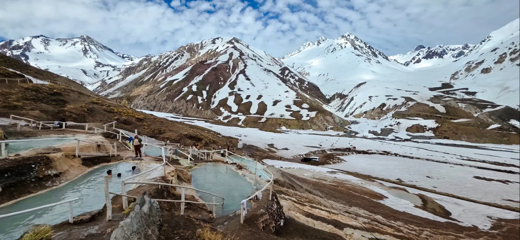 Thermal pools at Termas Baños Colina with snow-capped Andes in Cajon del Maipo, Santiago.