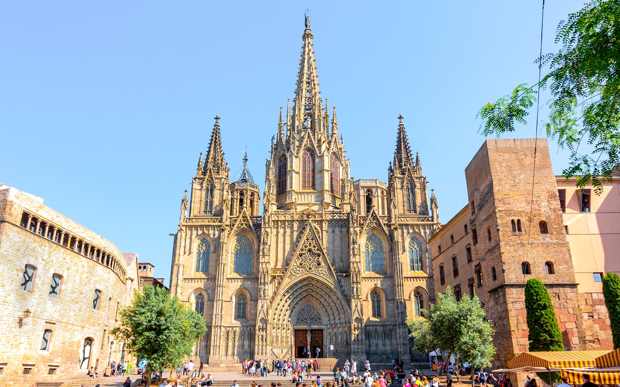 Cathedral of Barcelona exterior with Gothic spires and tourists in the foreground.