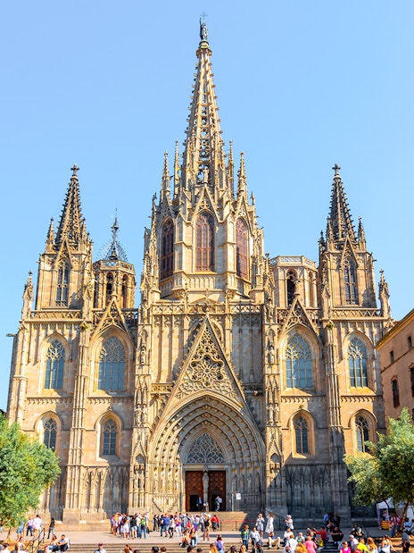 Cathedral of Barcelona exterior with Gothic spires and tourists in the foreground.