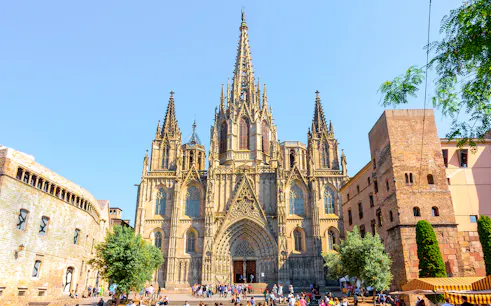 Cathedral of Barcelona exterior with Gothic spires and tourists in the foreground.