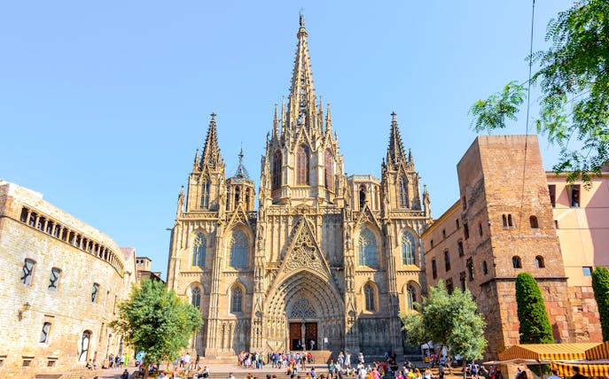 Cathedral of Barcelona exterior with Gothic spires and tourists in the foreground.