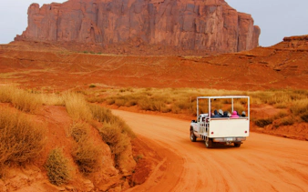 Truck on Monument Valley Loop Drive with red rock formations in the background.