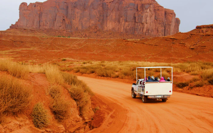 Truck on Monument Valley Loop Drive with red rock formations in the background.