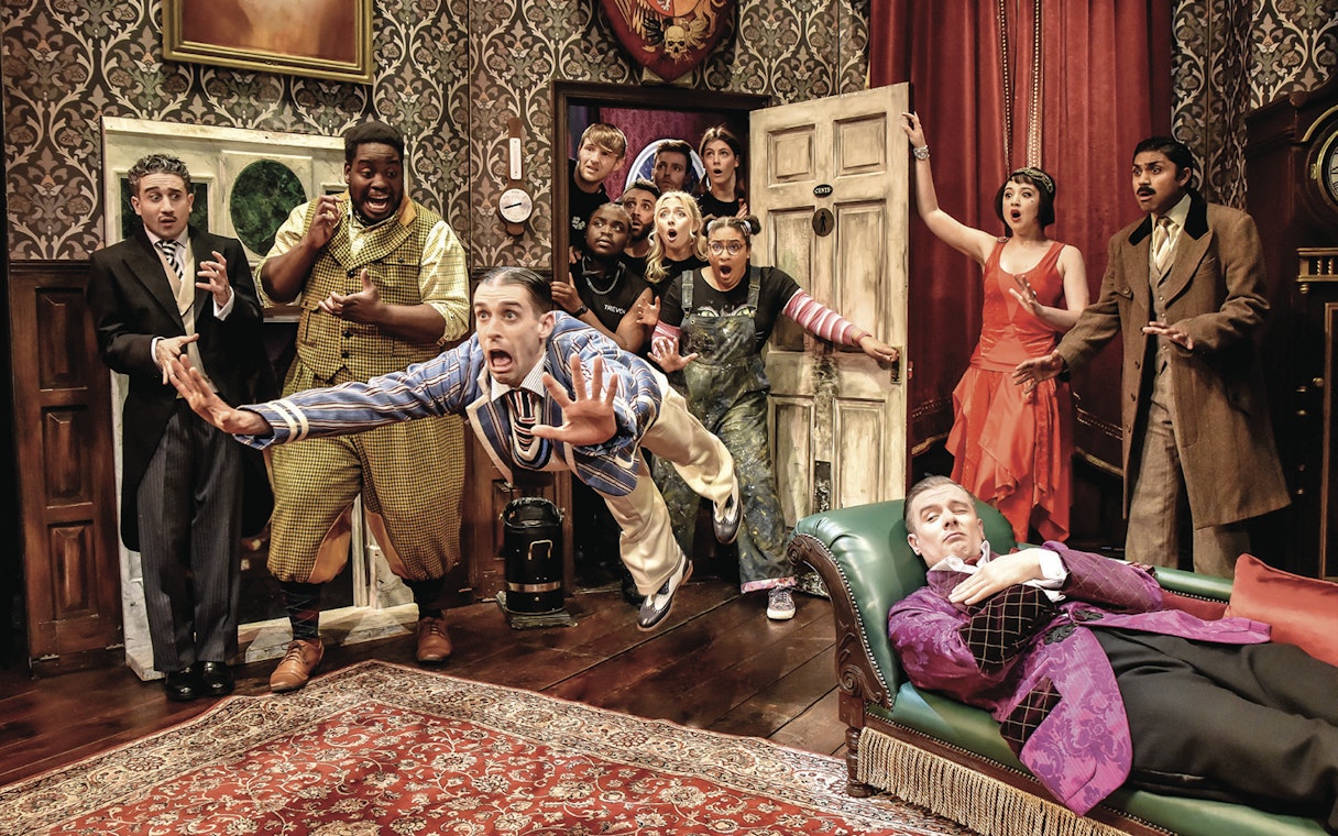 Actors in a chaotic scene from "The Play That Goes Wrong" on stage.