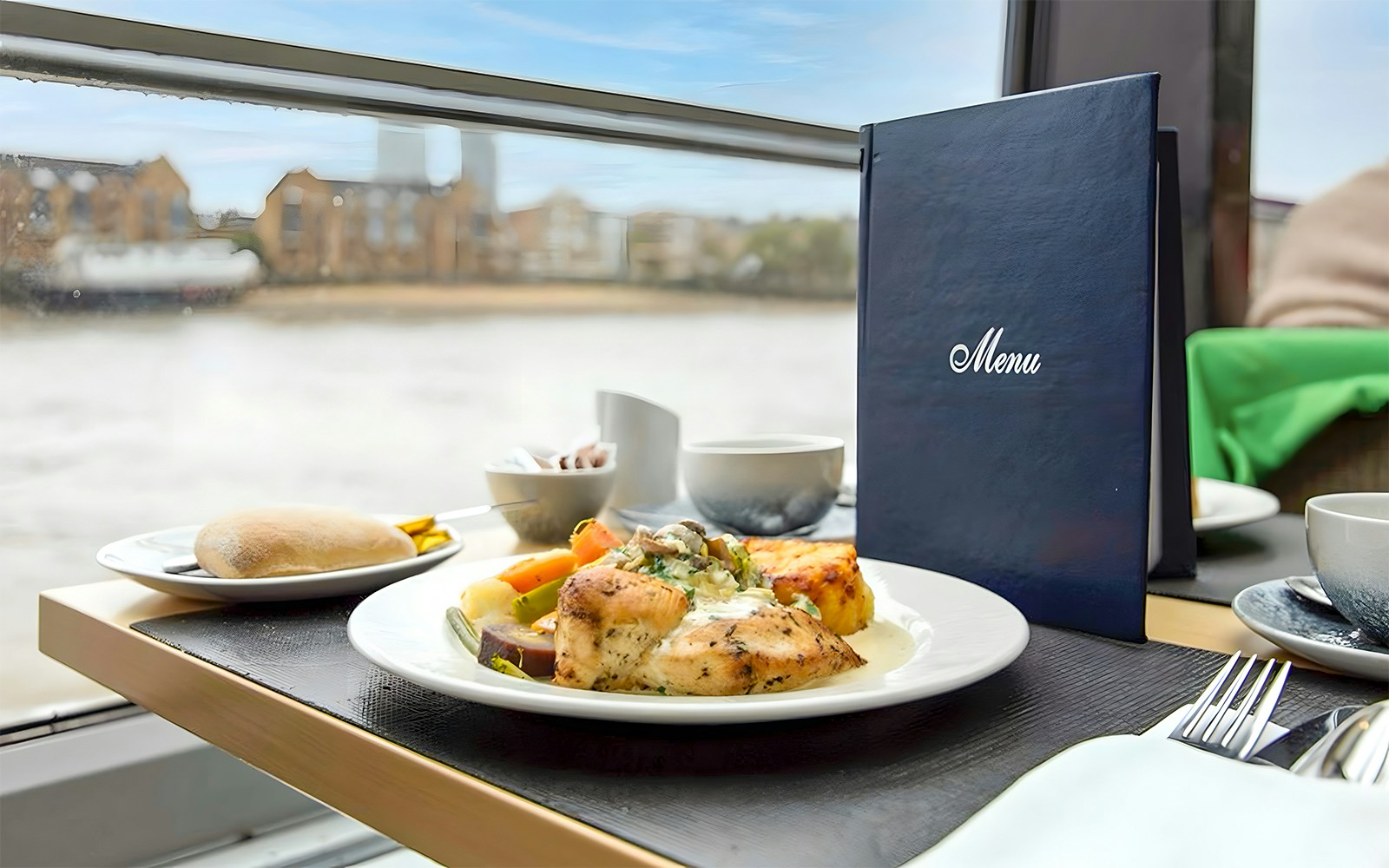 People dining on a Thames River cruise with views of London landmarks.