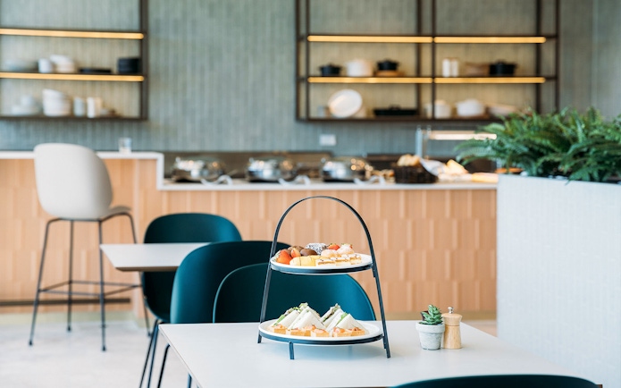 Plaza Premium Lounge dining area with tiered snack tray and modern seating.