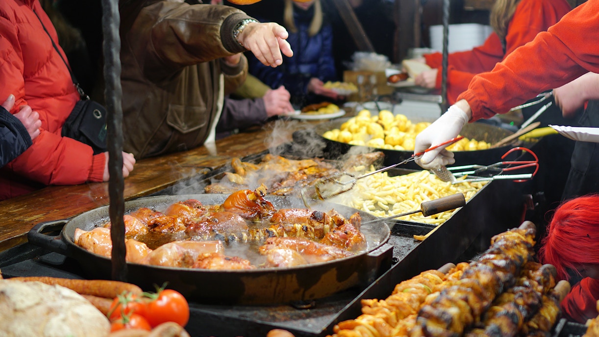 Street food vendors serving grilled meats and potatoes