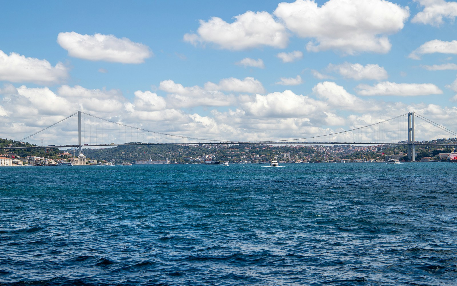 Bosphorus cruise ship with tourists viewing Istanbul skyline and landmarks, including the Hagia Sophia.