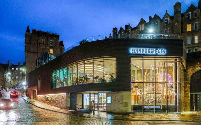 Edinburgh Gin distillery exterior at night with illuminated copper stills.