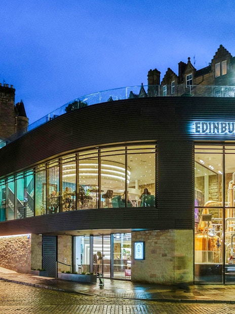 Edinburgh Gin distillery exterior at night with illuminated copper stills.
