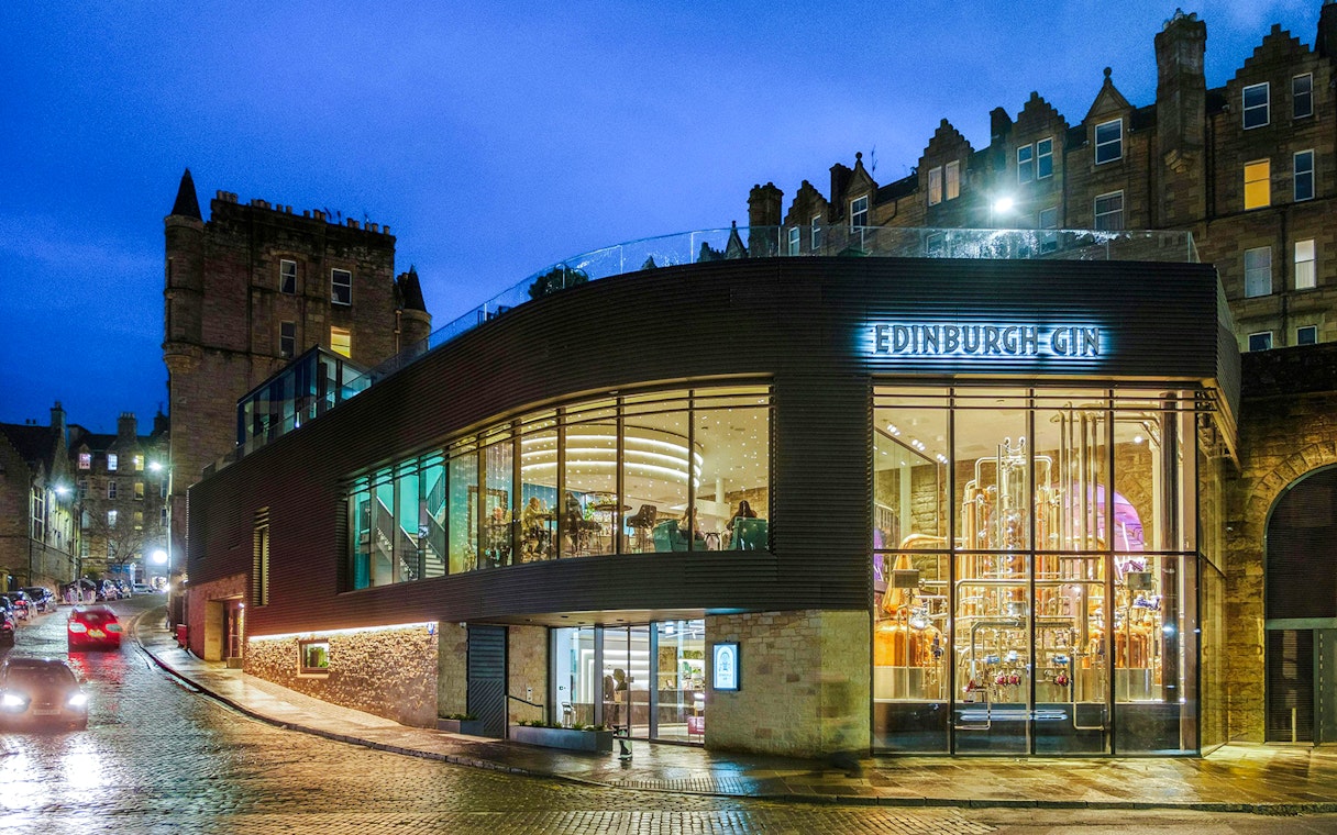 Edinburgh Gin distillery exterior at night with illuminated copper stills.