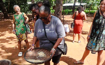 Participants engaging in traditional grain winnowing at Duruma Wedding Demo Village, Diani Beach.