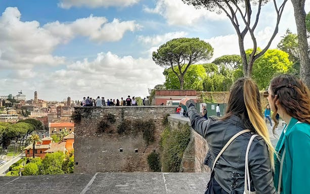 Tourists enjoying a panoramic view of Rome from a historic vantage point.