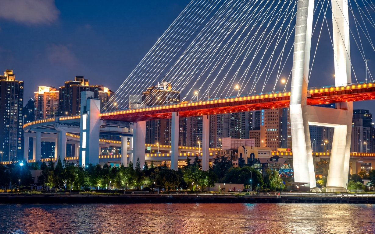 Nanpu Bridge in Shanghai lit with red and white lights at night.