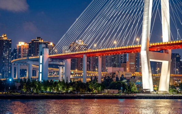 Nanpu Bridge in Shanghai lit with red and white lights at night.