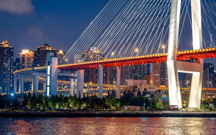 Nanpu Bridge in Shanghai lit with red and white lights at night.