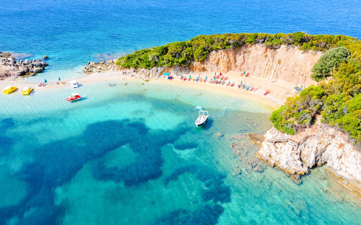 Aerial view of Ksamil beach with sun loungers and a boat in Saranda, Albania.