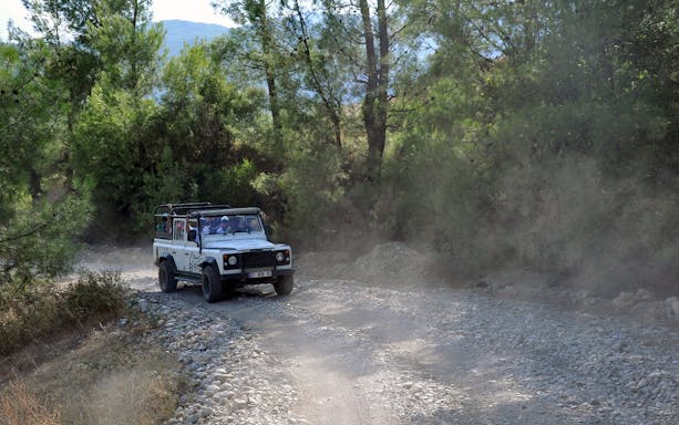 Jeep driving on a rocky trail through a forest in Antalya during a guided safari tour.