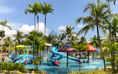 Family enjoying water slides at A'Famosa Melaka Waterpark, Malaysia, surrounded by palm trees.
