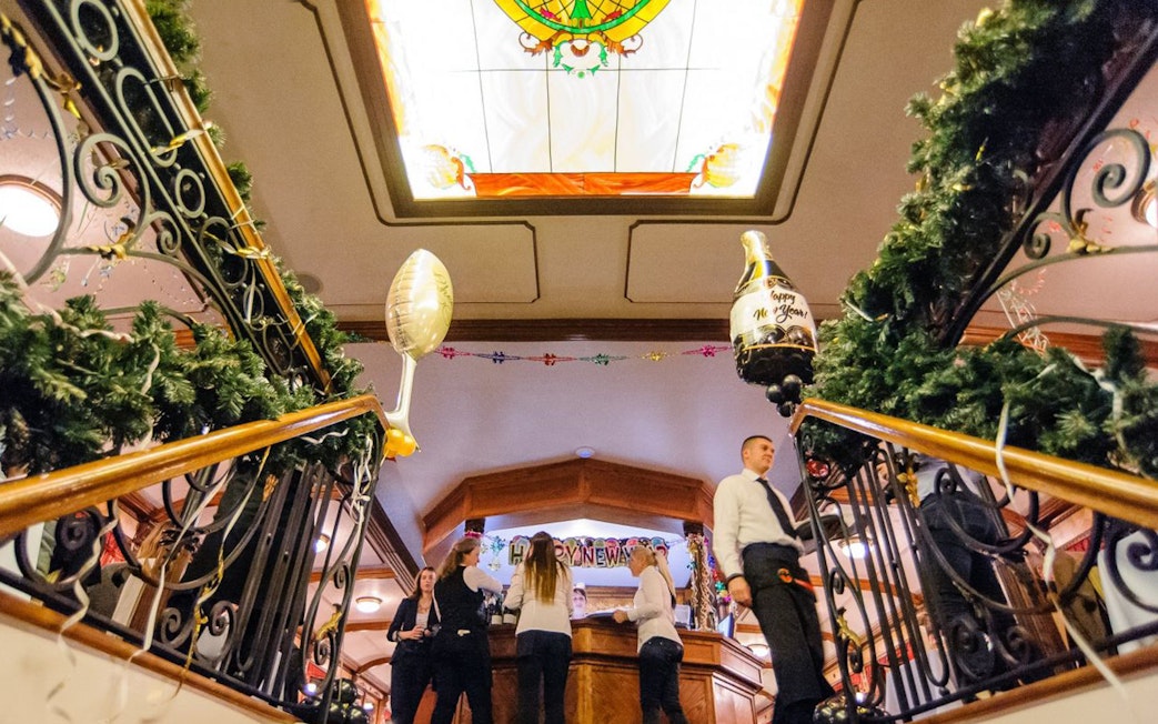 New Year’s Eve cruise guests at bar with festive decorations in Budapest.