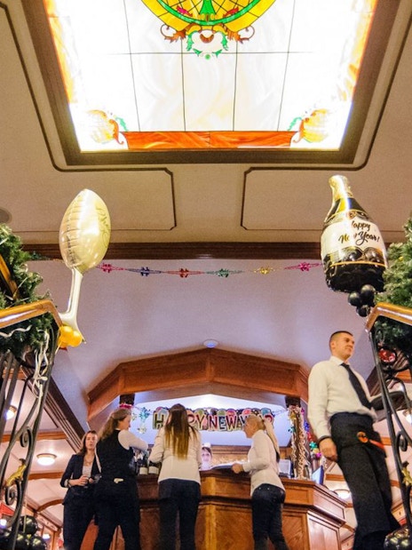 New Year’s Eve cruise guests at bar with festive decorations in Budapest.