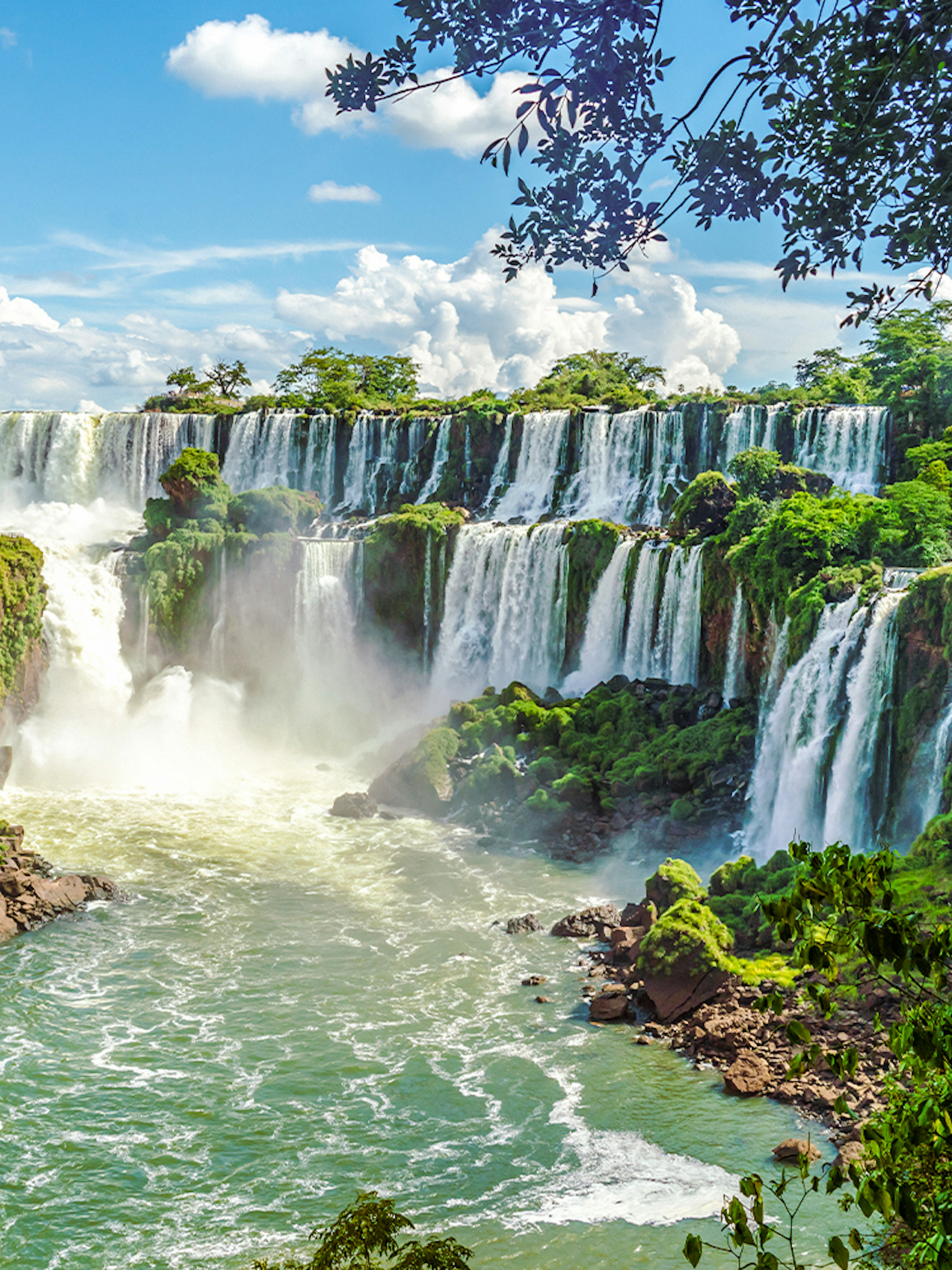 Iguazu Falls cascading over lush cliffs in Argentinian National Park.