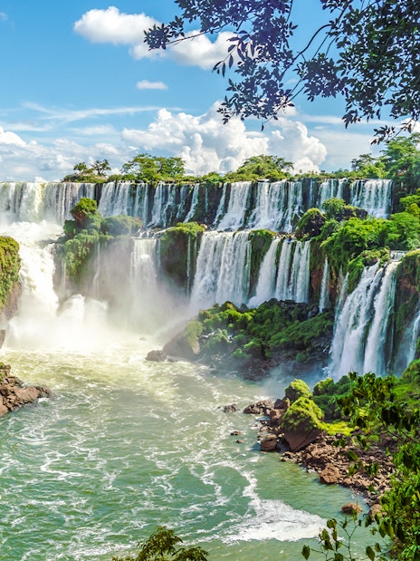 Iguazu Falls cascading over lush cliffs in Argentinian National Park.